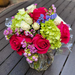 Bouquet of pink roses, white roses, and green hydrangeas in a glass vase