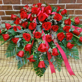 Large arrangement of red roses with pink ribbons