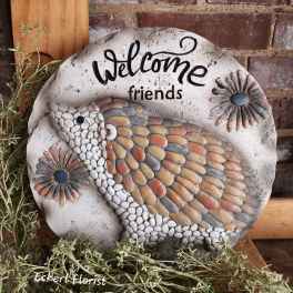 Round decorative stone plaque with a bird and "Welcome friends" text