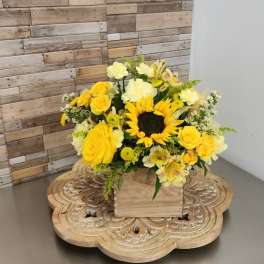 Yellow floral arrangement with a sunflower and roses in a wooden box