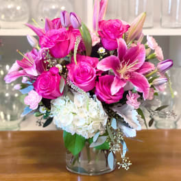 Pink roses and lilies arranged with white hydrangea in a glass vase