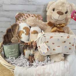 Gift basket with a teddy bear, candles, slippers, and a cosmetic bag