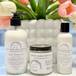 Tulips behind three goat milk skincare products on a white surface