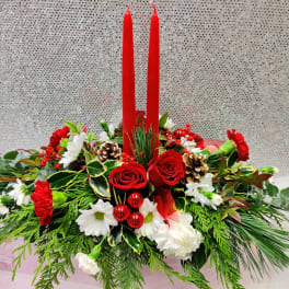 Red candles in a holiday floral centerpiece with roses and white blooms