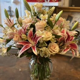 Bouquet of pink lilies, cream roses, and alstroemeria in a glass vase