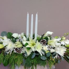 White floral centerpiece with three tall candles and pinecones