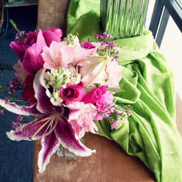 Pink and white bouquet with lilies and roses beside a green draped fabric