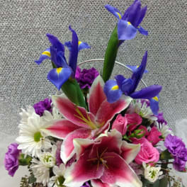 Basket arrangement with pink lilies, blue irises, and white daisies