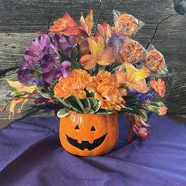 Halloween bouquet in a jack-o'-lantern mug with orange and purple flowers