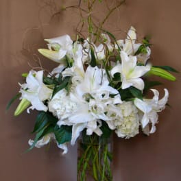 White lilies and hydrangeas in a tall glass vase
