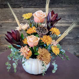 Autumn floral arrangement in a white pumpkin vase with roses and mums