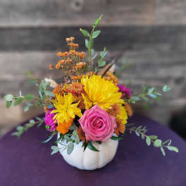 Mixed bouquet in a white pumpkin vase with a pink rose and yellow blooms