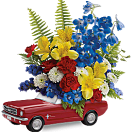 Flower arrangement in a red toy car with blue, yellow, red, and white blooms