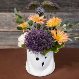 Peach and purple flowers arranged in a white ghost-shaped vase