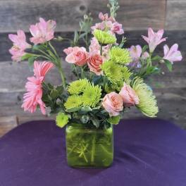 Pink and green mixed bouquet in a square glass vase