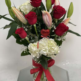 Red roses and white hydrangeas in a glass vase with a red ribbon