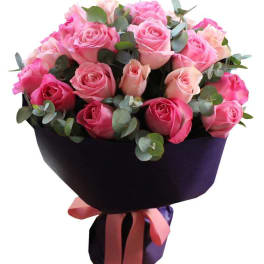 Bouquet of pink roses wrapped in dark paper with a ribbon