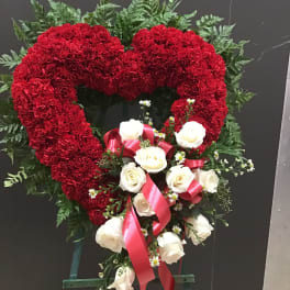 Heart-shaped red carnation wreath with white roses and pink ribbon
