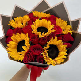 Bouquet of red roses and yellow sunflowers wrapped in dark paper