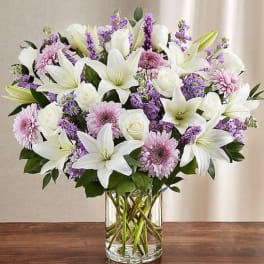 White lilies and pink flowers in a clear glass vase