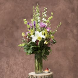 Tall bouquet of lilies, roses, and mixed blooms in a glass vase