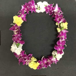 Purple and white orchid lei with yellow accents on a black surface