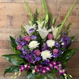Tall bouquet of white lilies, purple orchids, and pink roses in a vase