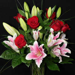 Bouquet of red roses and pink lilies in a clear glass vase