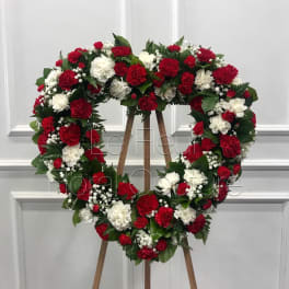 Heart-shaped wreath of red and white carnations on a wooden easel