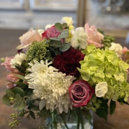 Mixed bouquet of roses, hydrangeas, and white chrysanthemums in a glass vase