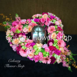 Pink and peach floral wreath around a silver urn