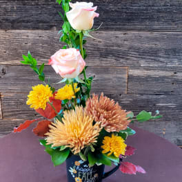 Fall floral arrangement in a black mug with pink roses and yellow chrysanthemums