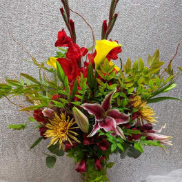 Tall mixed bouquet with red and yellow flowers in a glass vase
