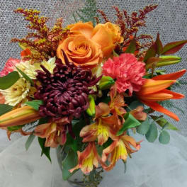 Bouquet of orange roses, lilies, and chrysanthemums in a glass vase