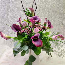 Purple calla lilies and pink roses in a white vase