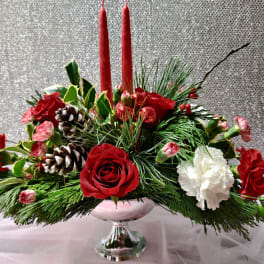 Christmas centerpiece with red roses, white carnations, and candles in a glass vase