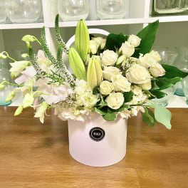 White roses and lilies arranged in a white hatbox