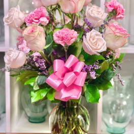 Pink roses and carnations in a glass vase with a pink ribbon