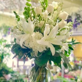 White lilies and roses arranged in a clear glass vase