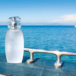Frosted perfume bottle on a boat railing with ocean behind it
