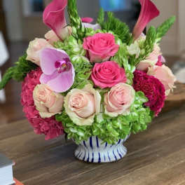 Pink roses and calla lilies arranged in a striped vase