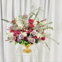 Mixed bouquet of roses and white blooms in a gold pedestal vase