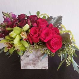 Pink roses and green orchids in a rustic square container