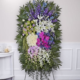 Tall standing floral spray with white lilies, orchids, and purple flowers