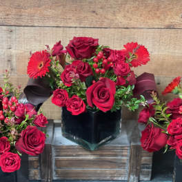 Red rose arrangement with gerbera daisies in a black vase