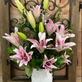 Pink and white lilies arranged in a white vase