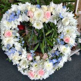 Heart-shaped floral wreath with white daisies, pink roses, and blue accents
