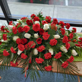 Large red and white floral casket spray on a table