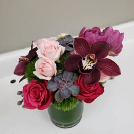 Bouquet of pink roses and dark orchids in a green vase