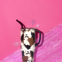 Cow-print travel tumbler with a black straw on a pink background